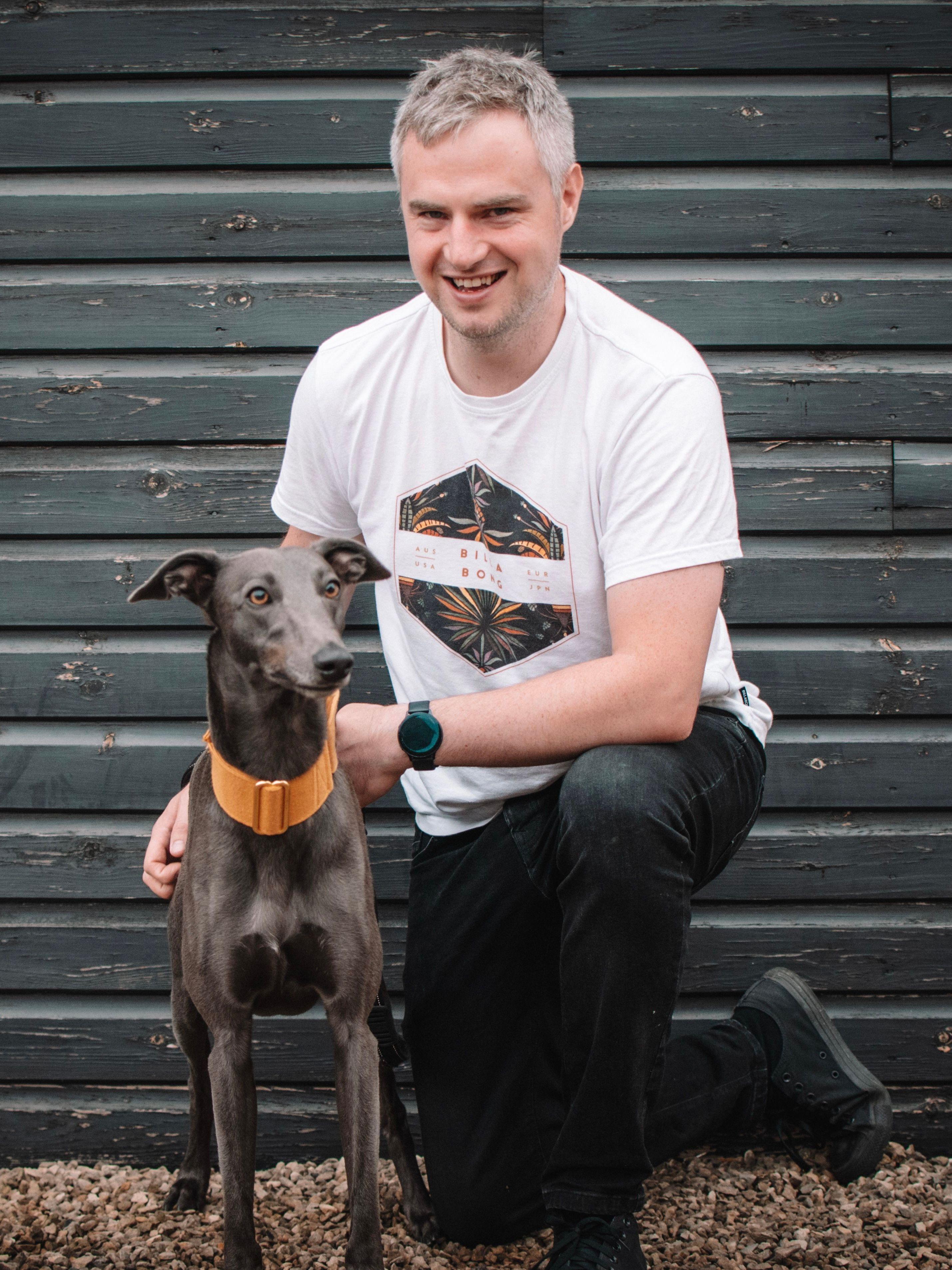Freestyle Full stack developer Mat Hope smiling and cuddling his greyhound dog Rodney.