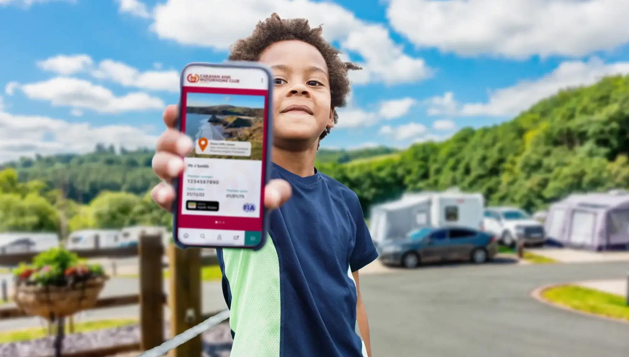 A child holding a phone displaying the Caravan and Motorhome Club booking app