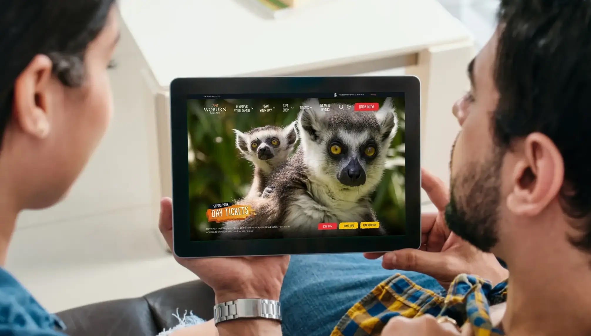 A couple holding an iPad showing the new Woburn Safari website